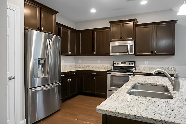kitchen featuring a sink, wood finished floors, dark brown cabinetry, and stainless steel appliances