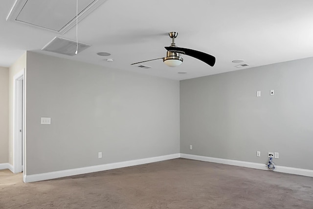 unfurnished room with visible vents, baseboards, attic access, and carpet flooring