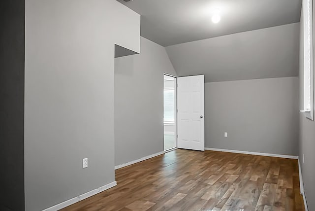 additional living space with baseboards, wood finished floors, and vaulted ceiling