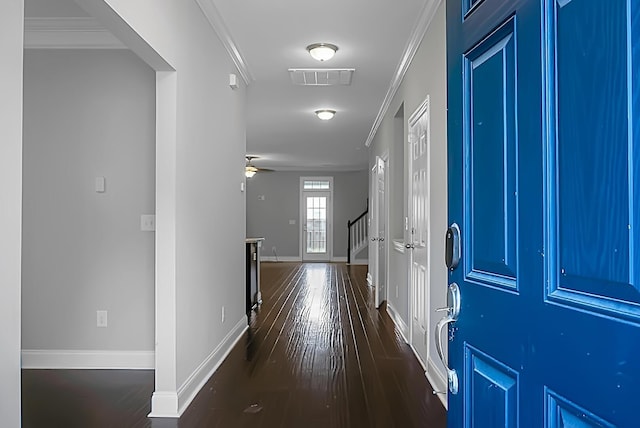 corridor with dark wood-style flooring, visible vents, baseboards, and crown molding