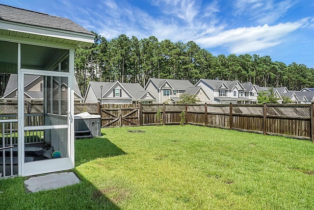 view of yard with a fenced backyard, a residential view, and a sunroom