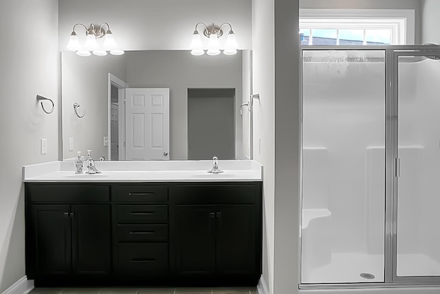 bathroom with a shower stall, double vanity, and a sink