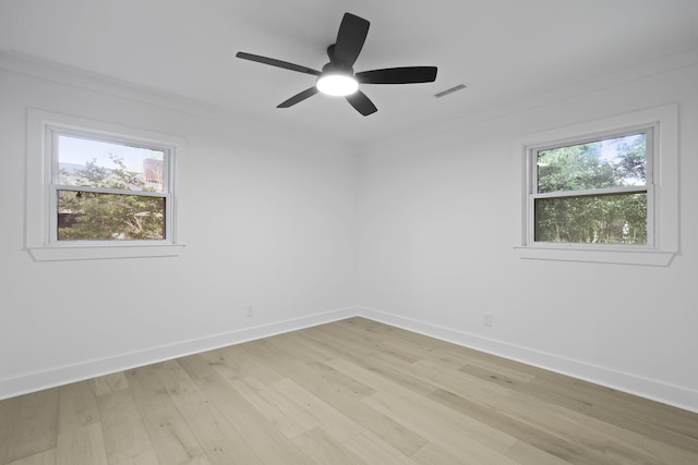 empty room featuring a ceiling fan, visible vents, crown molding, baseboards, and light wood finished floors