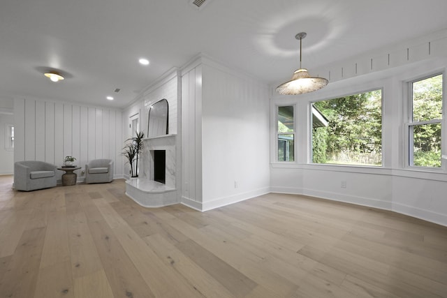 unfurnished living room featuring baseboards, light wood-style flooring, crown molding, and a premium fireplace