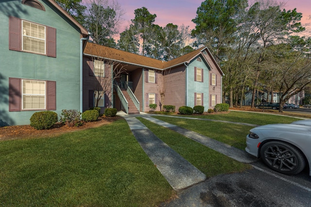 view of front facade with a lawn and stucco siding