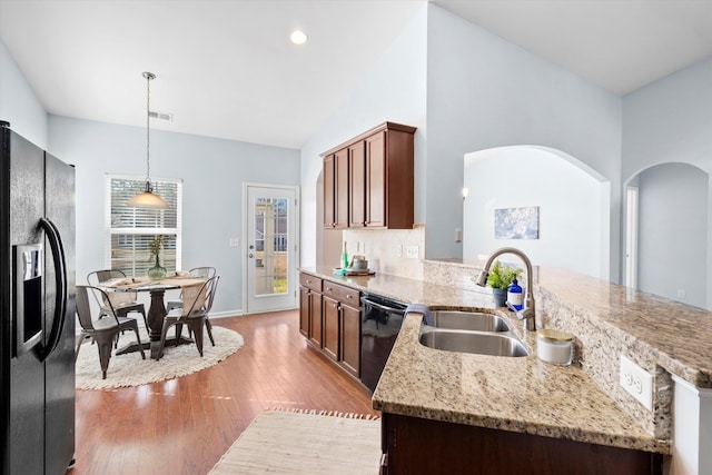 kitchen featuring wood finished floors, visible vents, light stone countertops, a sink, and black appliances