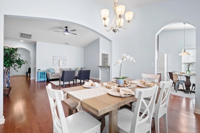 dining space featuring ceiling fan with notable chandelier, dark wood-type flooring, arched walkways, and visible vents