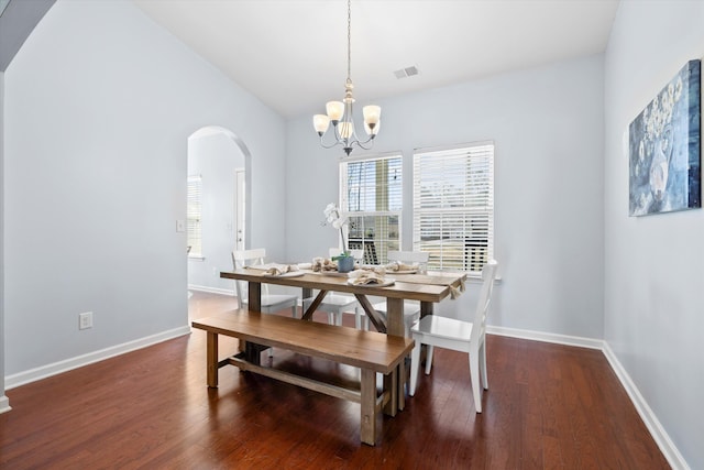 dining room with visible vents, baseboards, wood finished floors, arched walkways, and a notable chandelier