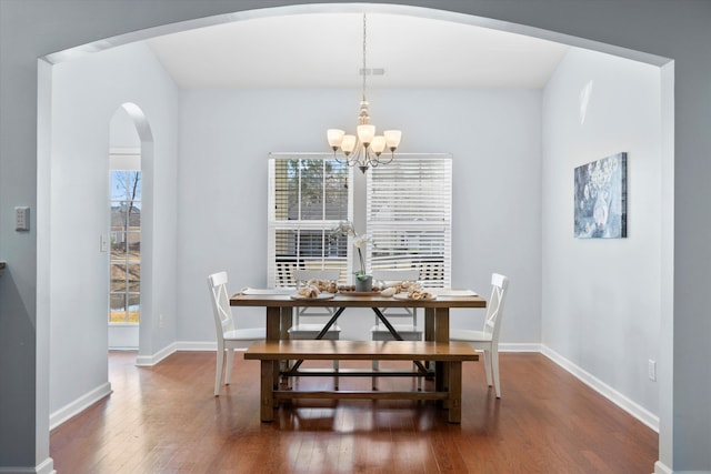 dining area featuring baseboards, arched walkways, a chandelier, and hardwood / wood-style flooring