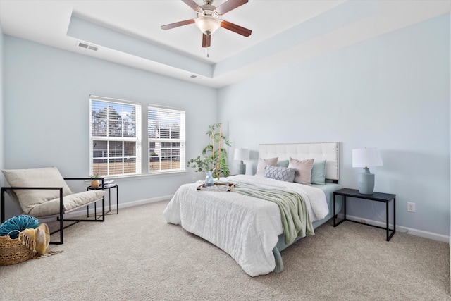 carpeted bedroom featuring visible vents, a raised ceiling, baseboards, and ceiling fan