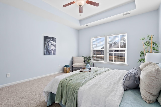 bedroom featuring a ceiling fan, carpet, visible vents, baseboards, and a raised ceiling