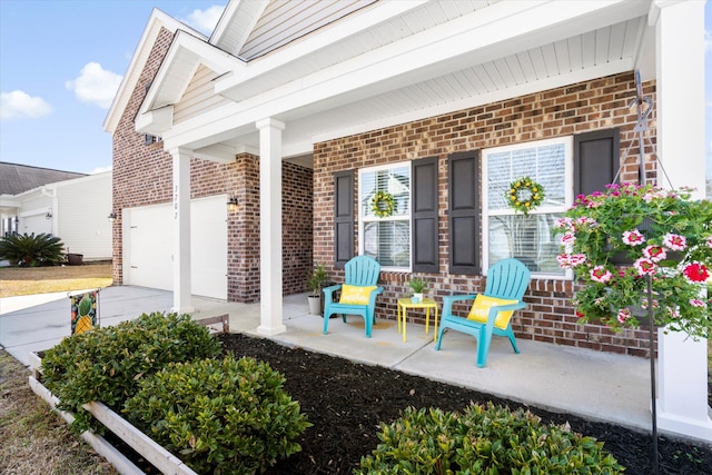 view of patio / terrace featuring covered porch, concrete driveway, and a garage