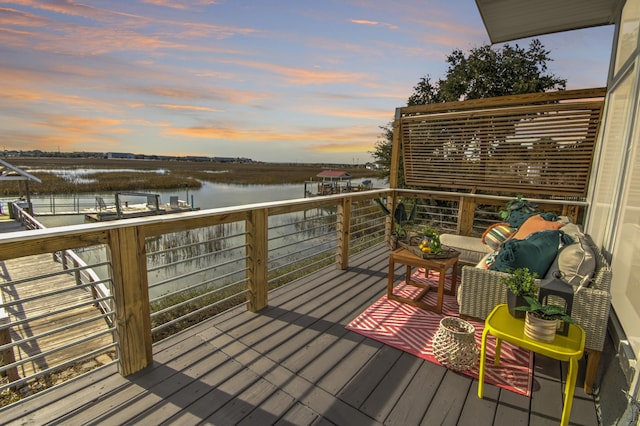 deck at dusk featuring a water view