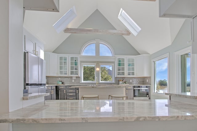 kitchen with white cabinets, tasteful backsplash, light stone countertops, and appliances with stainless steel finishes