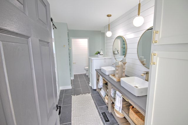 bathroom with wood walls, tile flooring, toilet, and vanity