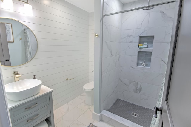 bathroom featuring vanity, a tile shower, and toilet