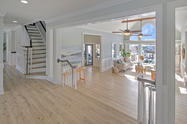 hall featuring plenty of natural light, ornamental molding, and light wood-type flooring