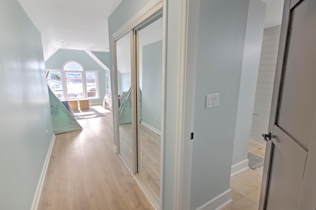 corridor with light hardwood / wood-style flooring and vaulted ceiling