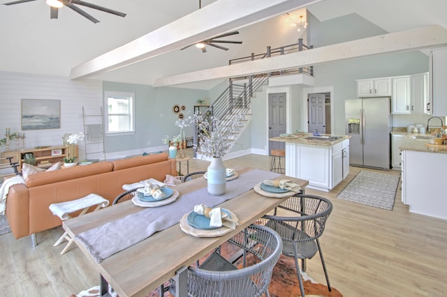 dining room with ceiling fan, sink, lofted ceiling with beams, and light hardwood / wood-style floors