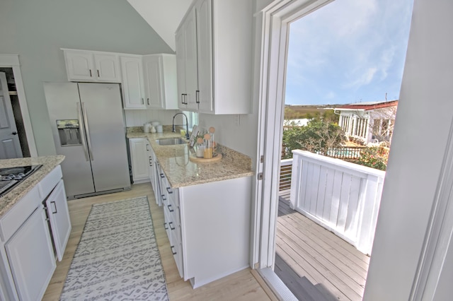 kitchen featuring sink, stainless steel refrigerator with ice dispenser, white cabinets, and a wealth of natural light