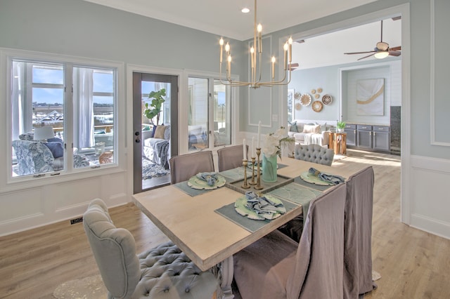 dining room with ornamental molding, light wood-type flooring, and ceiling fan with notable chandelier