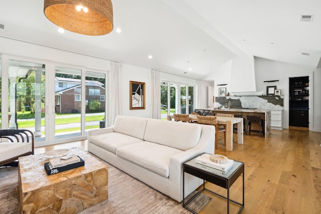 living room featuring lofted ceiling and light hardwood / wood-style floors