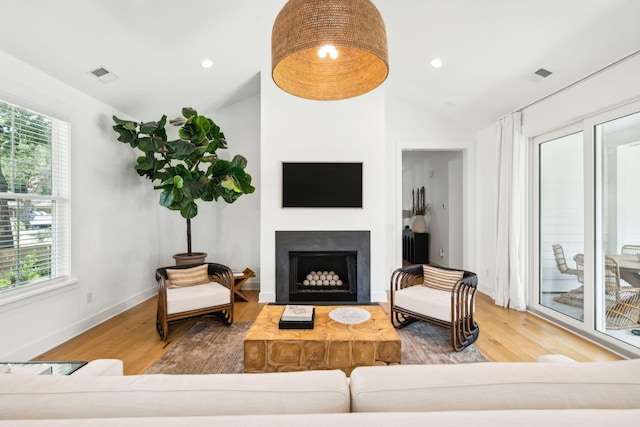 living room with a wealth of natural light, vaulted ceiling, and hardwood / wood-style flooring