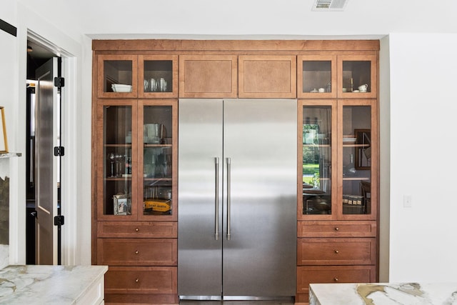 kitchen featuring light stone countertops and stainless steel built in fridge