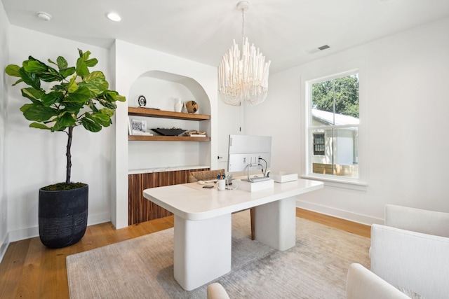 office space with an inviting chandelier and light hardwood / wood-style floors