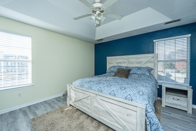 bedroom featuring multiple windows, wood-type flooring, and a textured ceiling