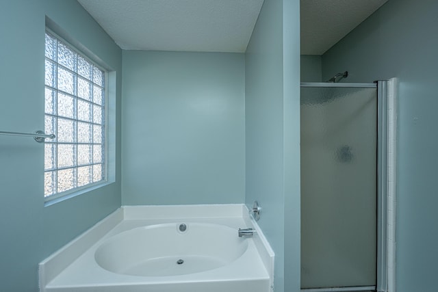 bathroom featuring shower with separate bathtub and a textured ceiling