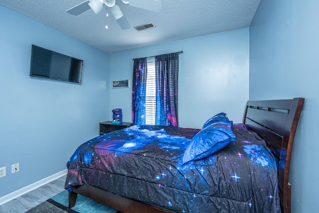 bedroom featuring ceiling fan, hardwood / wood-style flooring, and a textured ceiling