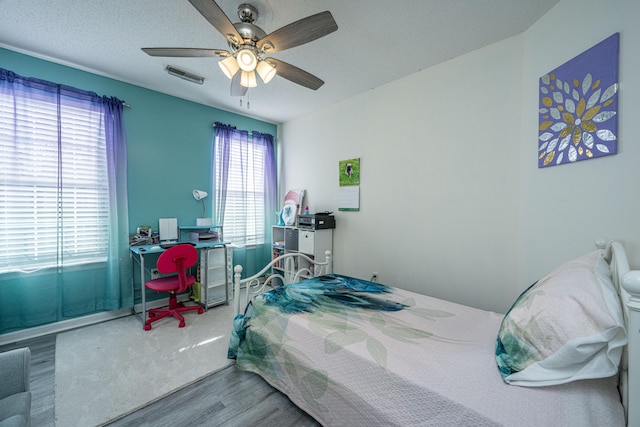 bedroom featuring hardwood / wood-style floors, a textured ceiling, and ceiling fan