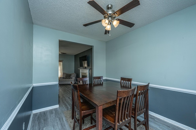 dining area with dark wood-type flooring, ceiling fan, and a textured ceiling