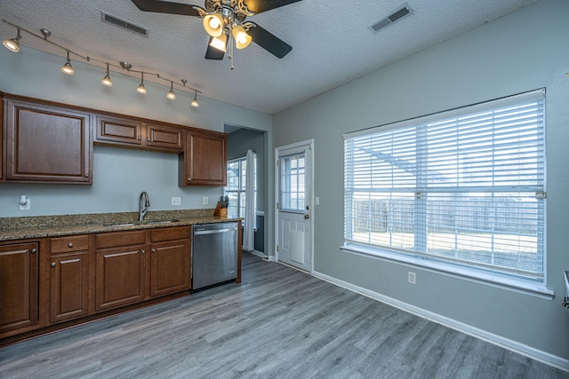 kitchen featuring dishwasher, sink, light wood-type flooring, light stone counters, and a textured ceiling