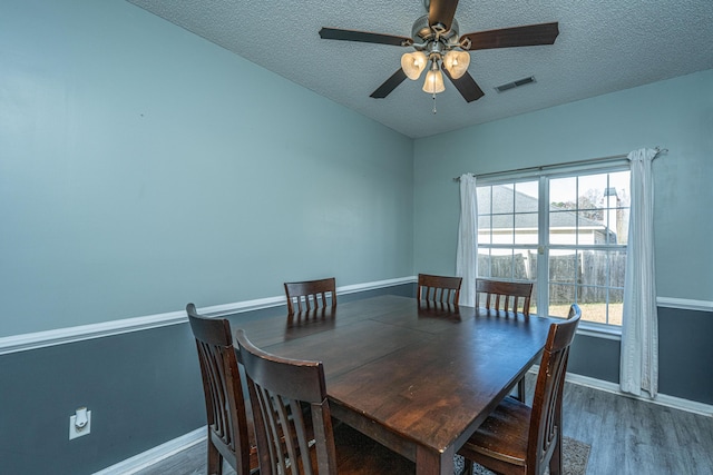 dining area with dark hardwood / wood-style flooring, ceiling fan, and a textured ceiling