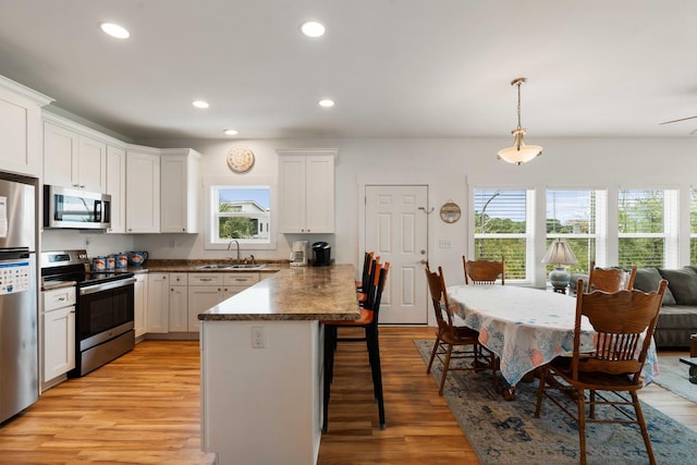 31 W 9th St, Folly Beach, SC 29439 - kitchen featuring appliances with stainless steel finishes, a breakfast bar, white cabinets, light wood-type flooring, and recessed lighting
