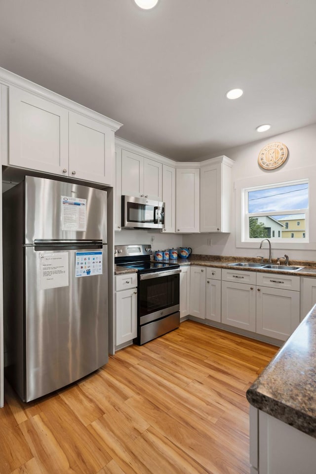 31 W 9th St, Folly Beach, SC 29439 - kitchen with appliances with stainless steel finishes, light wood-type flooring, white cabinets, recessed lighting, and dark stone countertops