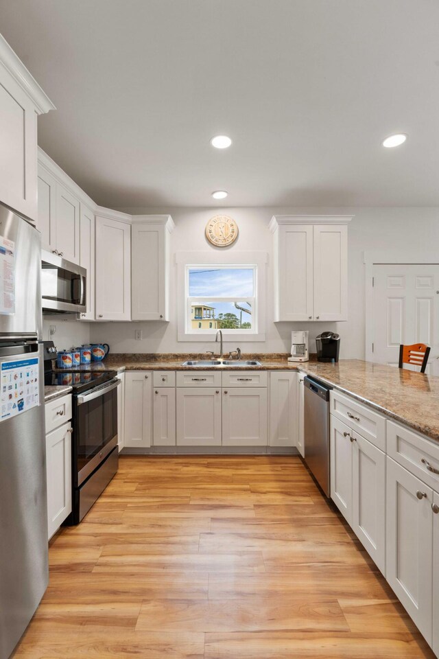 31 W 9th St, Folly Beach, SC 29439 - kitchen with appliances with stainless steel finishes, white cabinets, recessed lighting, light wood-style flooring, and light stone countertops