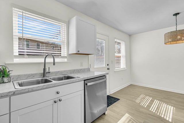 kitchen with a sink, stainless steel dishwasher, a wealth of natural light, and light countertops