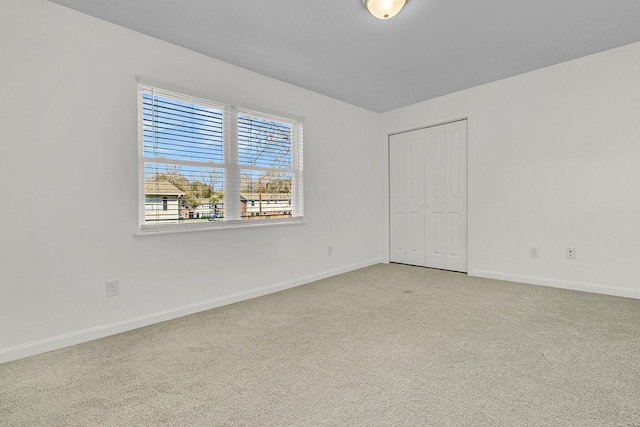 unfurnished room with baseboards and light colored carpet