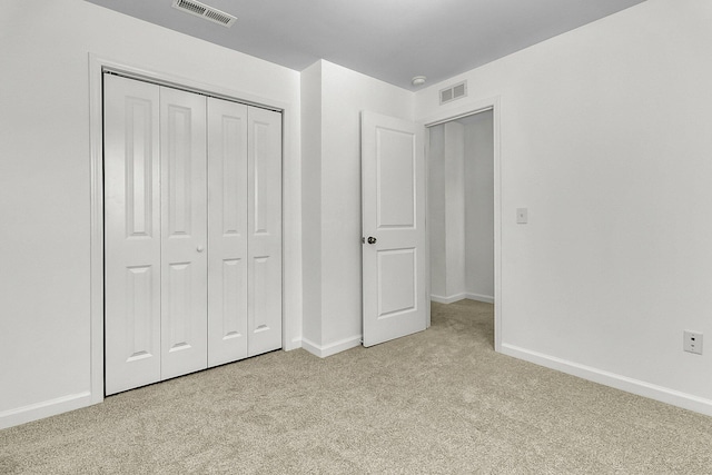 unfurnished bedroom featuring visible vents, baseboards, light colored carpet, and a closet