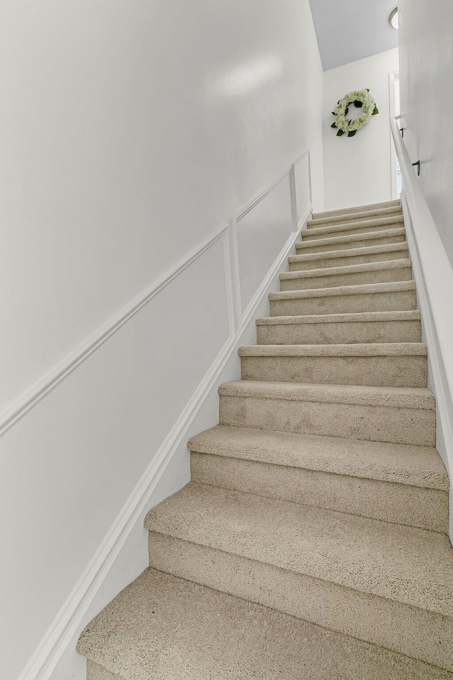 stairway featuring a decorative wall and a wainscoted wall