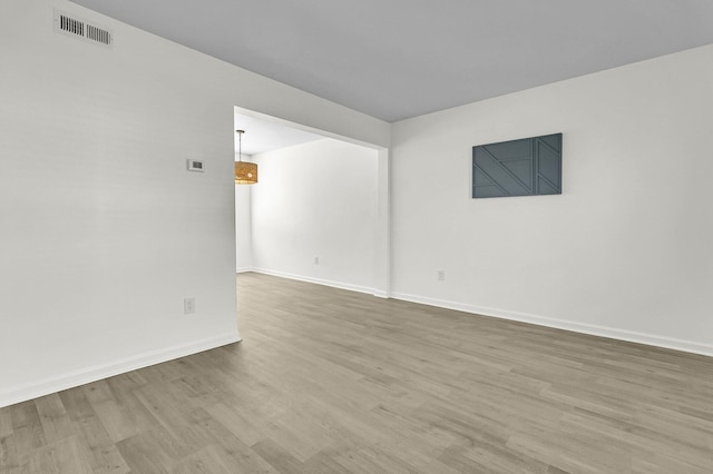 spare room with visible vents, baseboards, and wood finished floors