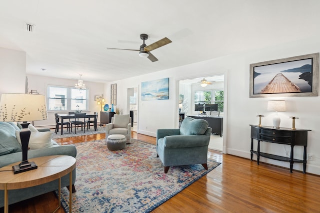 living room with wood-type flooring, ceiling fan with notable chandelier, and a wealth of natural light