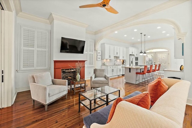 living room featuring ceiling fan, ornamental molding, dark hardwood / wood-style floors, and sink