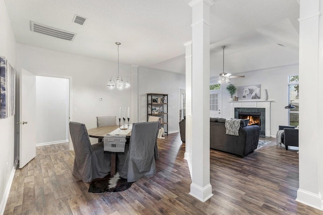 dining area with a textured ceiling, ceiling fan with notable chandelier, a healthy amount of sunlight, a fireplace, and dark hardwood / wood-style floors