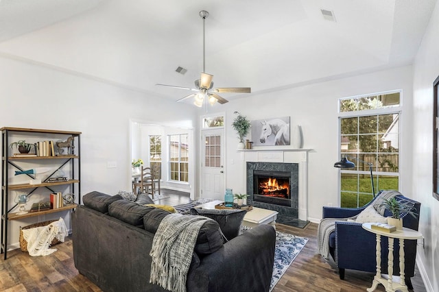 living room featuring vaulted ceiling, ceiling fan, dark wood-type flooring, and a premium fireplace