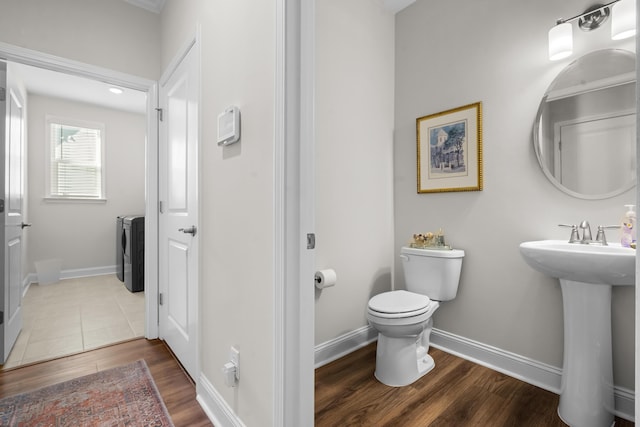 bathroom with wood-type flooring, washer / dryer, sink, and toilet