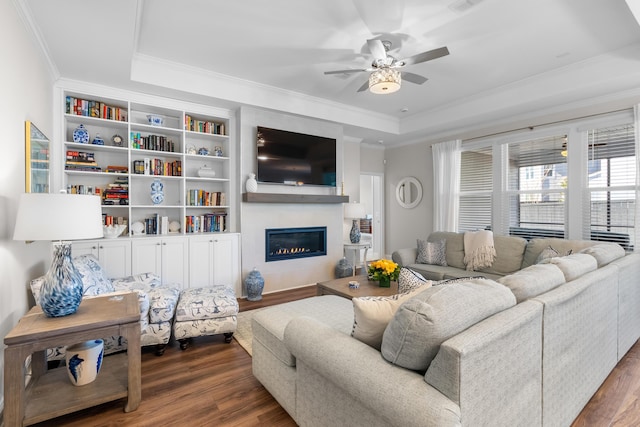 living room featuring ornamental molding, ceiling fan, dark hardwood / wood-style flooring, and a tray ceiling